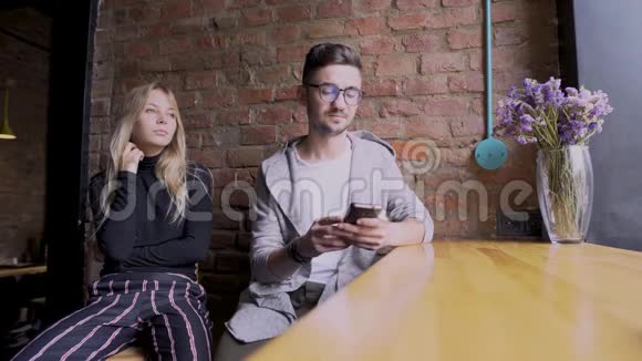 女孩和男孩在咖啡厅说话用智能手机工作视频的预览图