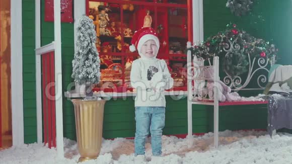 戴着圣诞帽和针织毛衣的微笑小男孩扔花视频的预览图