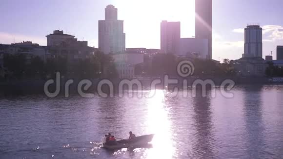 在夕阳和城市的背景下在湖上乘船下面的动作高清1920x1080视频的预览图