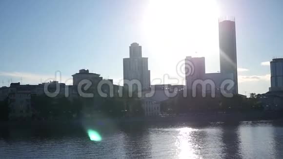 城市景观的背景下一个阳光湖与眩光和桨与一个男人和女孩漂浮在桨上视频的预览图