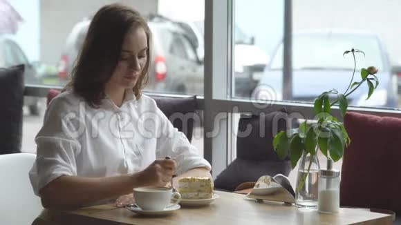 那个女孩坐在咖啡馆里享受着一杯芬芳的咖啡和甜蜜的蛋糕女商人休息视频的预览图