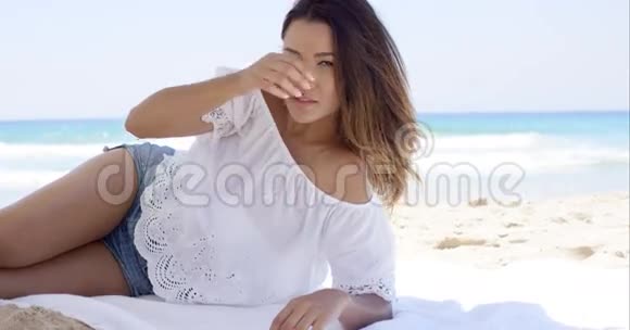 在沙滩伞下放松的漂亮女人视频的预览图