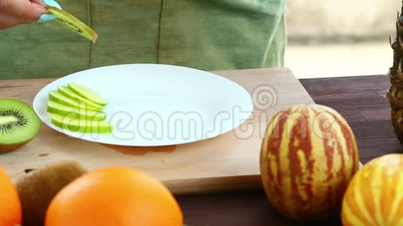 素食一个女人把一块猕猴桃放在一个切割板上放在盘子上视频的预览图
