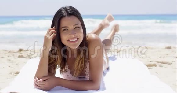 嘲笑快乐的年轻女人在海滩上晒太阳视频的预览图