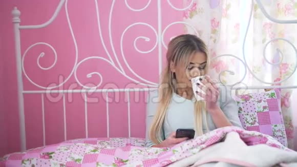 金发美女躺在床上在4K里喝酒和使用手机视频的预览图