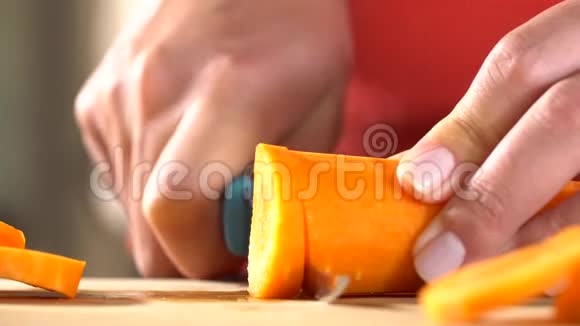 一个拿着刀的女人的手在家里的厨房里用一把刀刀切胡萝卜视频的预览图