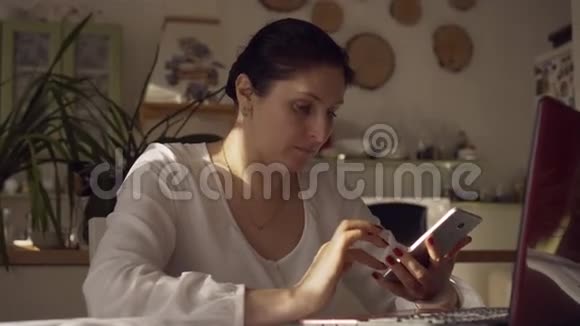 年轻的女设计师正在测试智能手机和电脑上的用户界面那个女人看电话女人坐着视频的预览图