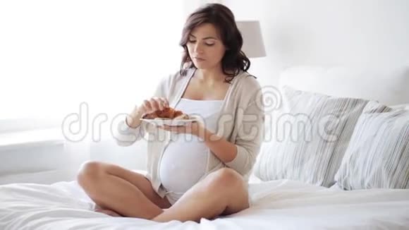 孕妇在家里的床上吃羊角面包视频的预览图