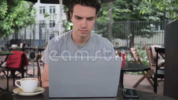 一个男人坐在咖啡馆的露台上打字视频的预览图