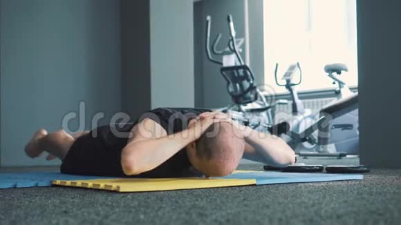 在蓝色黄色垫子上做伸展运动和热身运动时男人看起来很严肃视频的预览图
