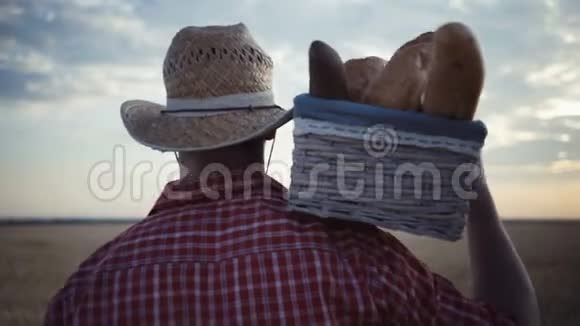 年轻的农民带着面包篮沿着麦田散步视频的预览图