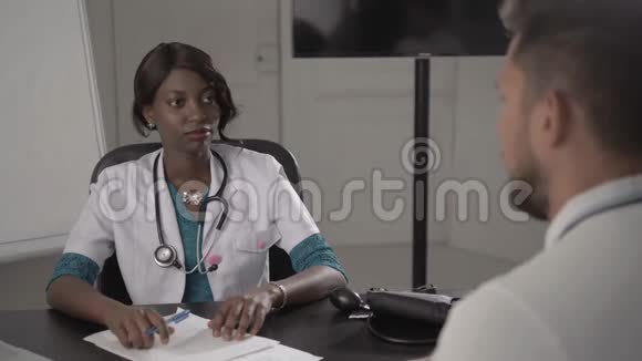 穿白大褂的医生在办公室检查男性病人血压非裔美国人医院的黑人护士视频的预览图
