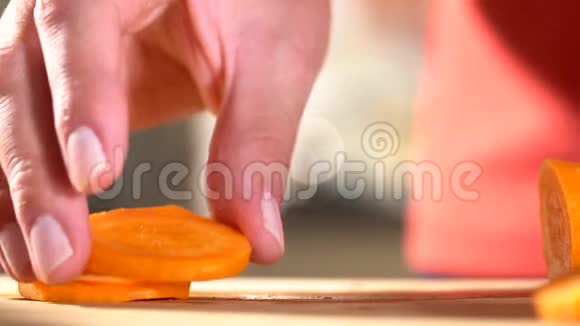 一个拿着刀的女人的手在家里的厨房里用一把刀刀切胡萝卜视频的预览图