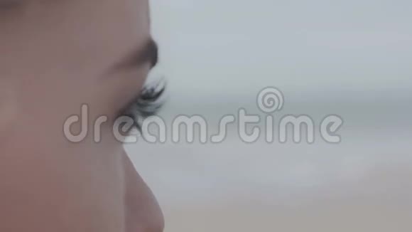 靠近年轻女子的眼睛看着孤独的海滩视频的预览图