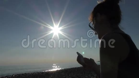 海滩上的年轻美女用手机视频的预览图