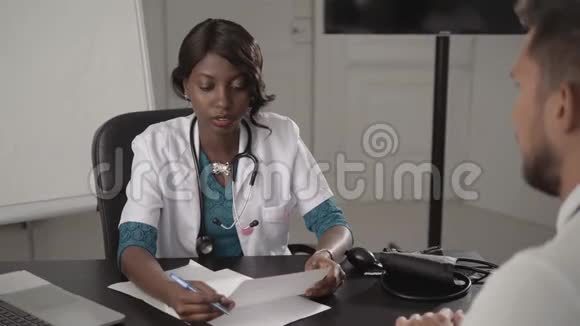 白衣医生在办公室检查男性病人血压非裔美国黑人护士在医院与视频的预览图