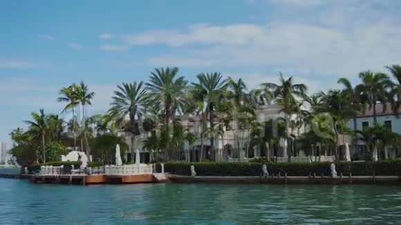 位于迈阿密阳光明媚的艾尔斯海滩上的星岛棕榈树和私人码头之间的豪华豪宅视频的预览图