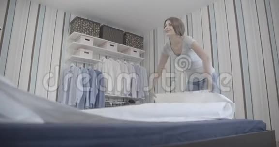 年轻女子微笑着把床整理成没有品位的样子视频的预览图