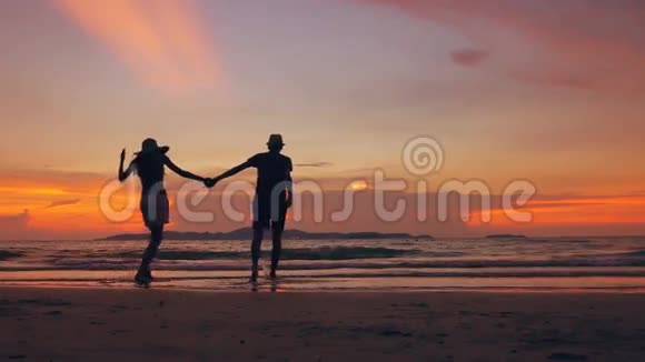 在海边的夕阳下一对幸福的情侣在海滩上相遇并玩耍视频的预览图