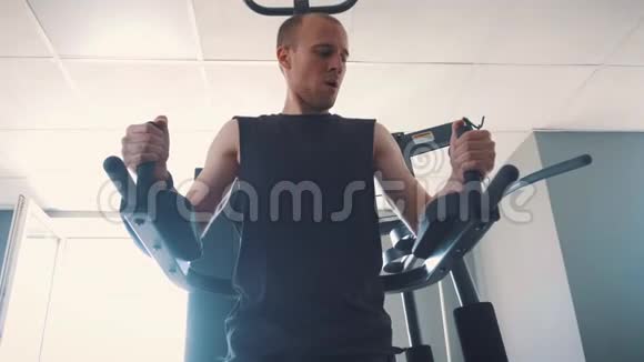 健身室的年轻肌肉男练划艇机视频的预览图