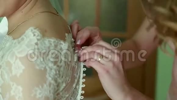伴娘正在为美丽的新娘系白色婚纱准备婚礼视频的预览图