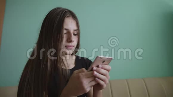 漂亮的金发白种人少女坐在家里的沙发上发短信微笑着笑着的女人爱情视频的预览图