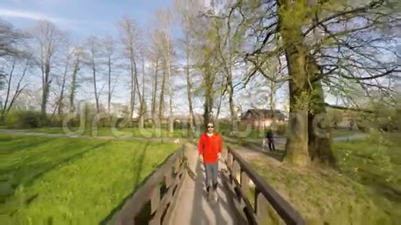 在公园里沿着桥奔跑的人的正面景色视频的预览图