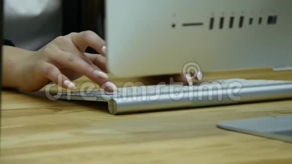 在桌子旁的现代办公室用电脑键盘上的女人手打字的特写镜头视频的预览图