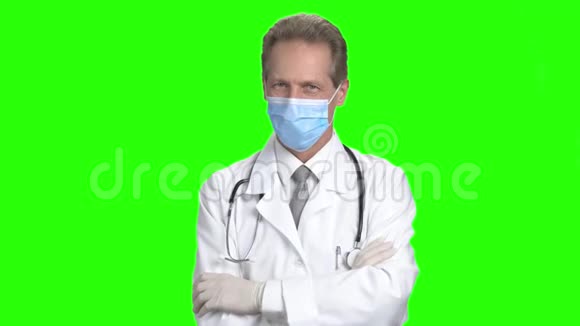 成熟的医生戴着防护面罩和折叠的手臂视频的预览图