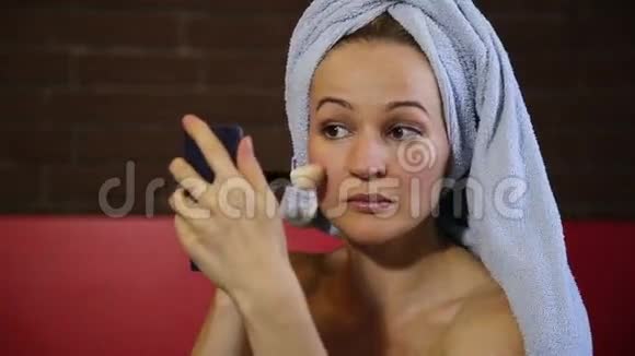 穿着浴巾的女人化妆脸颊上涂着红色皮肤护理日常面部皮肤美丽视频的预览图