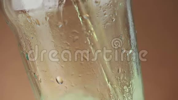 将泡沫的新鲜啤酒倒入带有冰冰冻滴的饮料品脱杯中置于金褐色背景下提供乐趣和营养食品视频的预览图