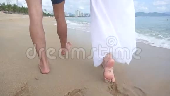 两个情人在海边散步和拥抱的后景沙子上的腿视频的预览图