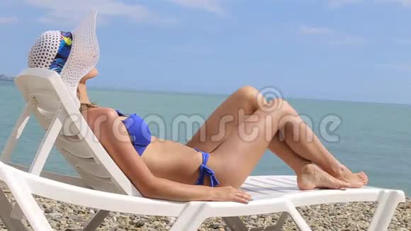 年轻女子在热带海滩上放松躺在沙滩躺椅上视频的预览图