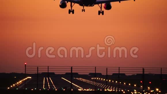 飞机在橙色夕阳的天空下侧影降落视频的预览图
