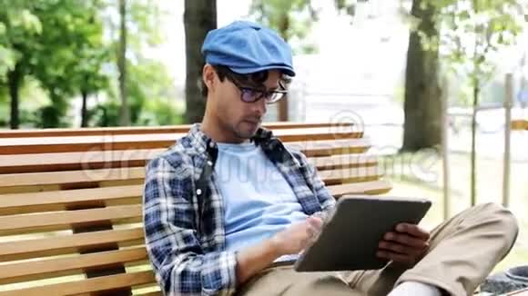 有平板电脑的人坐在城市街头的长凳上视频的预览图