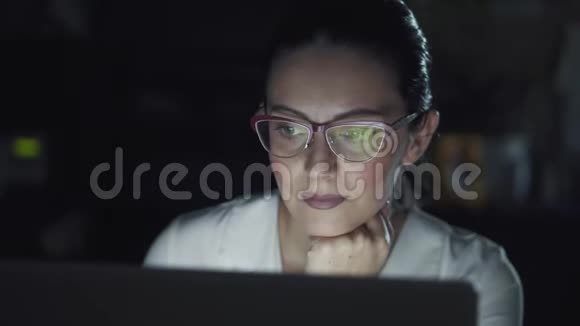 商务女性晚上在办公室工作用眼镜反射电脑屏幕视频的预览图