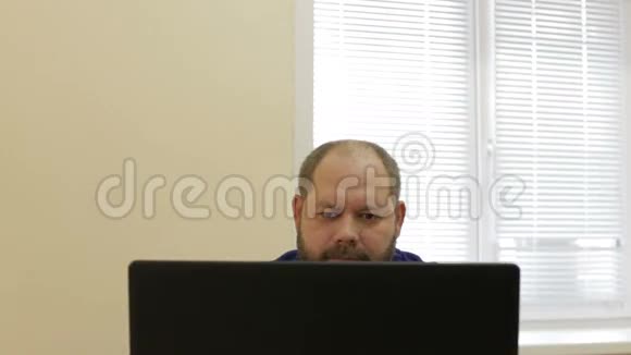 有胡须的成年男性坐在电脑工作场所视频的预览图