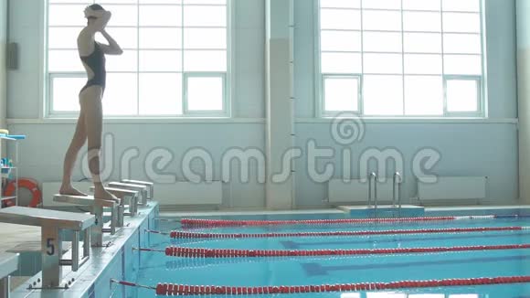 年轻的女游泳运动员那跳跃和跳水进入室内运动游泳池视频的预览图