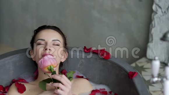 小女孩躺在一个大石头浴缸里手里拿着一朵玫瑰花视频的预览图