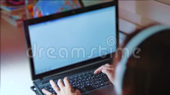 小女孩带着耳机在笔记本电脑上玩网络游戏电脑上的小女孩用生活方式写了一条信息视频的预览图