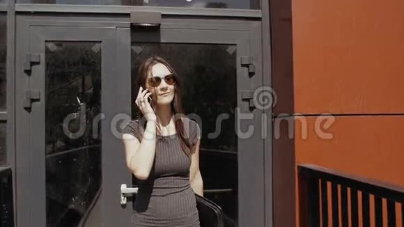 商务女性使用智能手机步行接近在建商务大楼Stealicam射击慢节奏视频的预览图