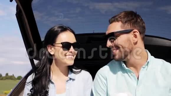 一对快乐的情侣在掀背车后备箱里喝咖啡视频的预览图