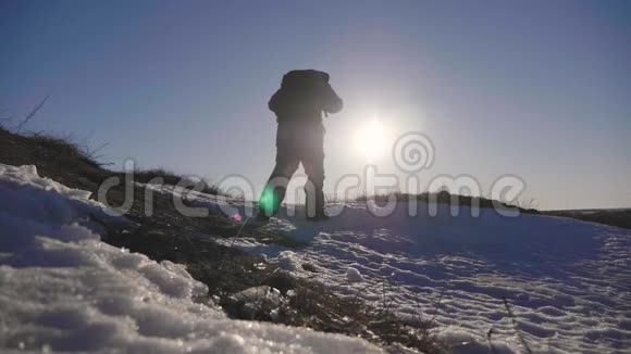 穿着雪鞋在冬天的风景中行走的人的剪影带着徒步旅行杆蓝天和视频的预览图