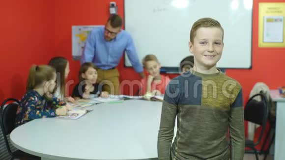 小男孩举着大拇指举着书和同学在后台学习视频的预览图