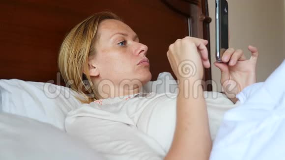 这位女士躺在床上使用智能手机4k慢动作视频的预览图