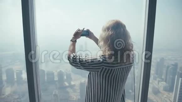 女游客站在窗口用手机拍照视频的预览图