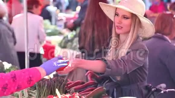 市场上漂亮的女孩摘西红柿视频的预览图
