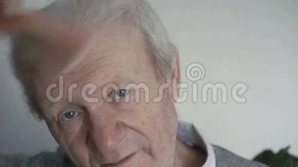 年纪轻轻的快乐老人正在用梳子梳理他的白发视频的预览图