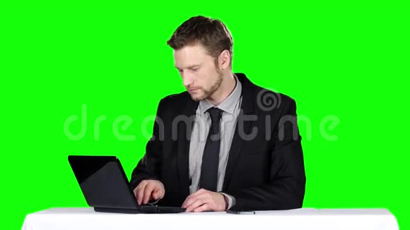 商人坐在办公桌前用笔记本打电话绿色屏幕视频的预览图