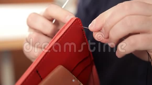 人用手做皮钱包一个人在皮夹上缝针视频的预览图